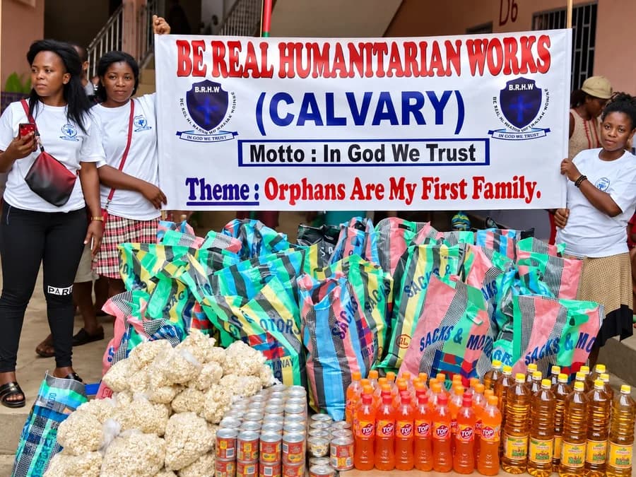 Be Real Humanitarian Works volunteers behind the organization's banner, with rice, cooking oil, tinned food and drinks ready to be distributed